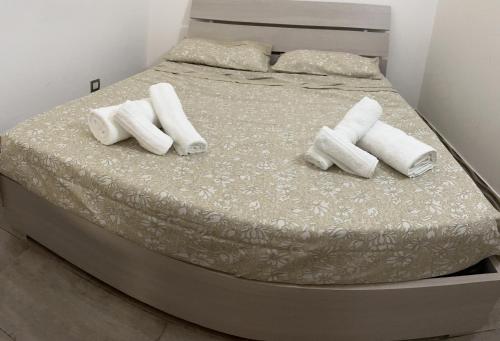 Una cama con almohadas blancas y toallas. en JASMINE HOUSE, en Triggiano