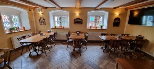 a restaurant with wooden tables and chairs and windows at Restaurant & Pension Liebenstein in Libá