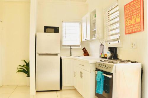 a white kitchen with a refrigerator and a stove at The Northside Cottage in St Thomas