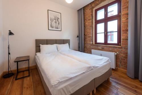 a bedroom with a large white bed with a brick wall at PROVENIR HOME KWIATOWA 5 in Poznań