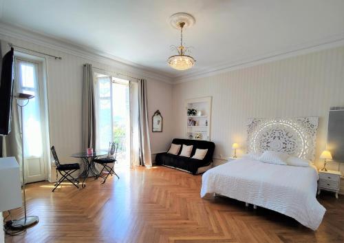 een slaapkamer met een wit bed en een bank bij Grand studio 38m2 dans ancien palace avec piscine et place de parking privée in Aix-les-Bains