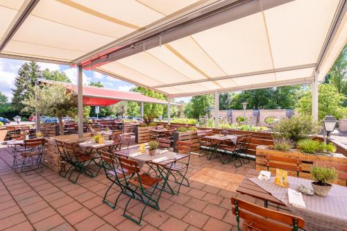 an outdoor patio with tables and chairs and white umbrellas at Zur Post Kümmersbruck Hotel & Tiny Houses in Kümmersbruck