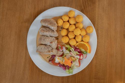 a plate of food with meat and vegetables and potatoes at Restaurant & Pension Liebenstein in Libá