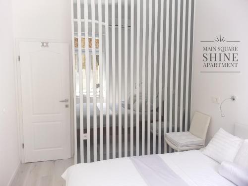 a white bedroom with a bed and a chair at Luxurios and historic apartment "Shine" - right on the Main Square in Zagreb