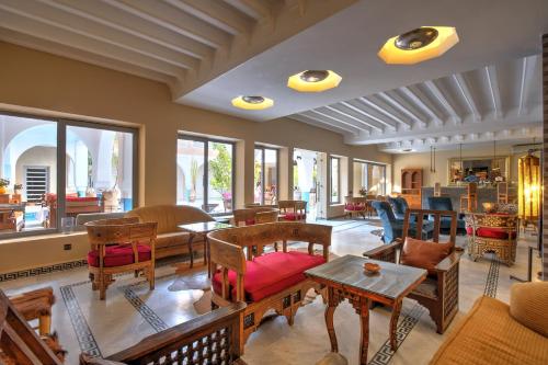 een woonkamer met stoelen, tafels en ramen bij Ksar Anika Boutique Hotel & Spa in Marrakesh
