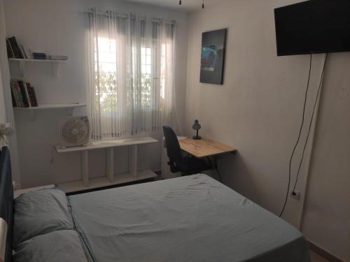 a bedroom with a bed and a desk and a window at Apartamento con piscina en primera linea de playa in Puerto de Mazarrón