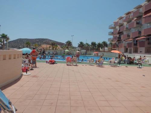a group of people standing around a swimming pool at Apartamento con piscina en primera linea de playa in Puerto de Mazarrón