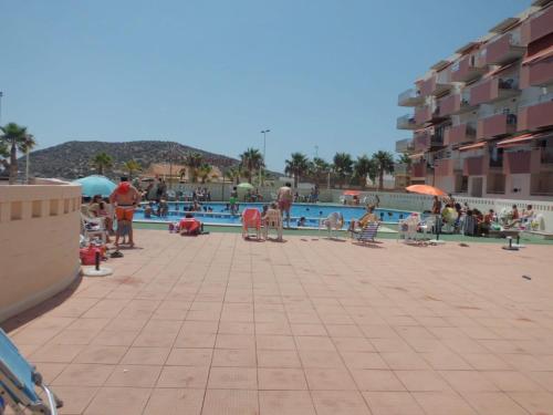 een groep mensen die rond een zwembad staan bij Apartamento con piscina en primera linea de playa in Puerto de Mazarrón