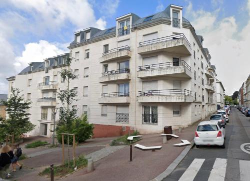 un gran edificio blanco con un coche aparcado delante de él en Le Garden Studio avec terrasse et parking centre ville, en Rouen