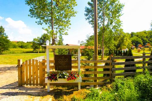 a wooden fence with a bench with a sign and flowers at Imanje Lotus Garden in Šabac