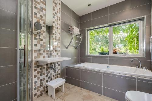 a bathroom with a tub and a sink and a window at Clonaslee House in Coleraine
