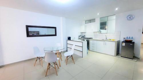 a white kitchen with a glass table and chairs at Departamento en Pacasmayo in Pacasmayo