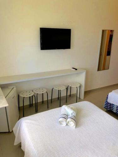 a bedroom with a bed with stools and a tv on the wall at FLATS VISTA MAR e FRENTE MAR NA PRAIA DOS CARNEIROS in Praia dos Carneiros
