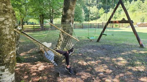 a person laying on a hammock in a park at Vikendica Kločanica in Strmosten