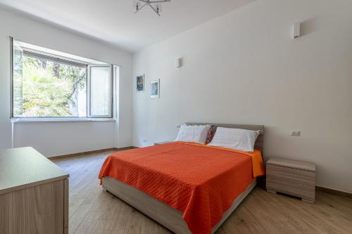 a bedroom with a bed with an orange blanket and a window at CityLife, Fiera City, MiCo & San Siro Apartment in Milan