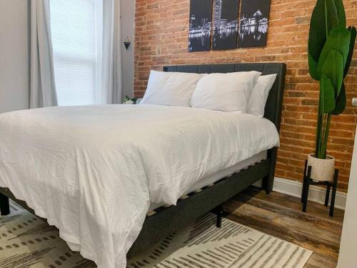 a bed with white sheets and a brick wall at Cozy Modern Apt in the Heart of Fells Point! in Baltimore