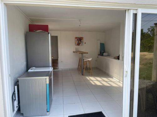 een keuken met een koelkast en een tafel bij La petite Girafe in Baie-Mahault