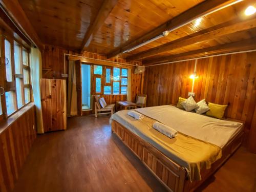 1 dormitorio con 1 cama grande en una habitación de madera en Pine Tower Inn, en Manali
