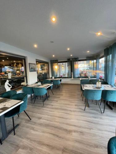 a restaurant with blue tables and chairs and windows at Strand Hotel Nordsee, Hotel Deichläufer in Tossens