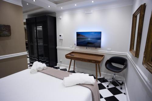カターニアにあるBorgo Santa Caterinaのベッド2台、デスク、テレビが備わる客室です。