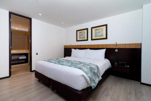 a hotel room with a large bed and a bathroom at Hotel Madisson Inn Luxury By GEH Suites in Bogotá