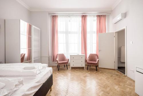 a white bedroom with a bed and two chairs at Prime Star Fashion street modern luxury apartments in Budapest