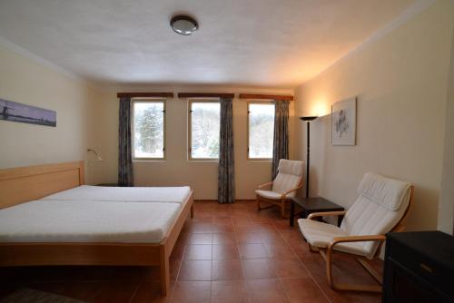 1 Schlafzimmer mit einem Bett, 2 Stühlen und Fenstern in der Unterkunft Kemp na Staré papírně in Dobronice