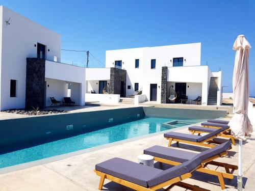 a swimming pool with lounge chairs next to a villa at myLithos Suites in Monolithos