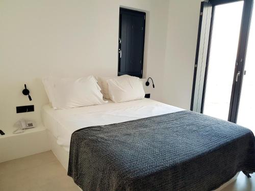 a bedroom with a bed with white sheets and a window at myLithos Suites in Monolithos