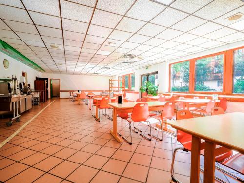 uma sala de jantar com mesas, cadeiras e janelas em Auberge de Jeunesse HI Chamonix em Chamonix-Mont-Blanc