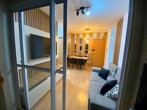 uma sala de estar com um sofá e uma sala de jantar em Apartamento com Sacada na Gleba, Novo e equipado em Londrina