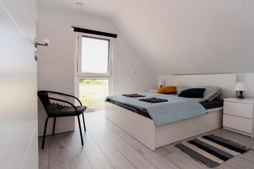 1 dormitorio blanco con 1 cama y 1 silla en Mazury Zakątek Salpia 1 dom apartament 10 osób Family 1, en Prażmowo