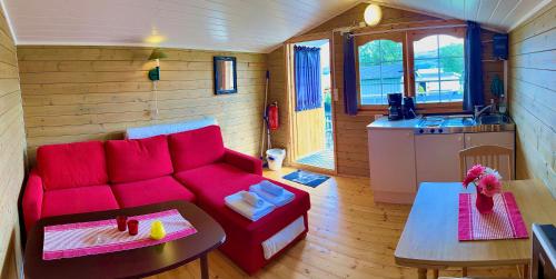 a living room with a red couch and a kitchen at Aspnes Camping AS in Mosjøen