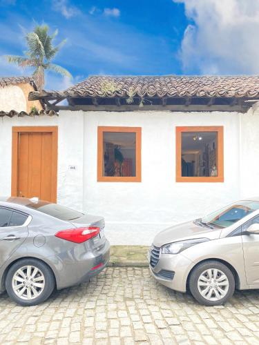 due auto parcheggiate di fronte a una casa bianca di Hostel Dona Generoza a Parati