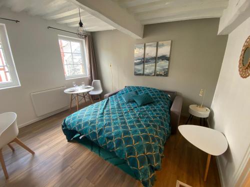 ein Schlafzimmer mit einem Bett mit einer grünen Bettdecke und einem Tisch in der Unterkunft Le studio bleu - studio hypercentre Rouen - 106 in Rouen