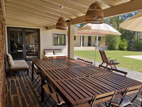 a wooden table with chairs and an umbrella on a patio at Quinta dos Morangueiros in Armamar