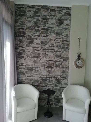twee stoelen en een tafel voor een stenen muur bij HOTEL LOFOS APARTMENT in Plakias
