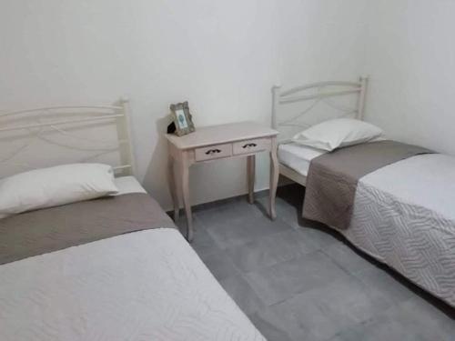 a room with two beds and a table with a night stand at HOTEL LOFOS APARTMENT in Plakias
