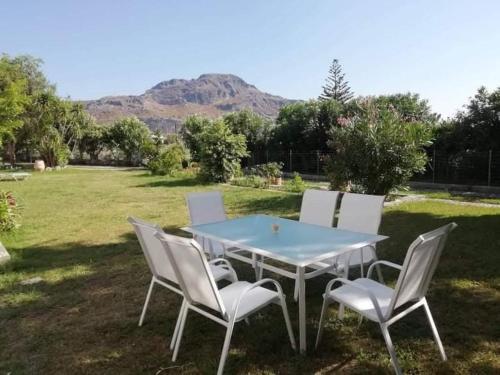 een tafel met vier witte stoelen en een blauwe tafel bij HOTEL LOFOS APARTMENT in Plakias