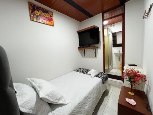 a small bedroom with a bed and a tv at Hostal Casa del Café in Bogotá