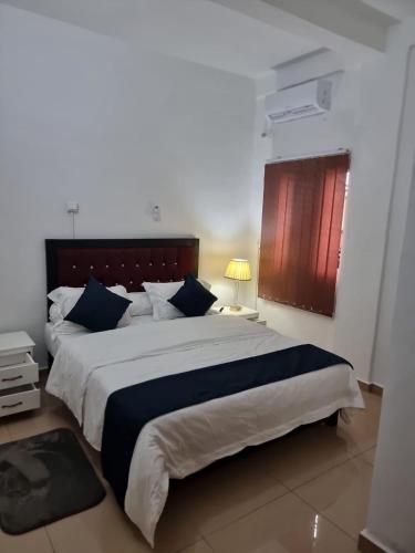 a bedroom with a large bed with blue pillows at Baobab Lodge Douala (Bonamoussadi) in Douala