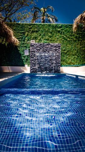a blue swimming pool with a chair and a fountain at Shark Town Mal Pais in Santa Teresa Beach
