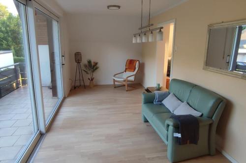 a living room with a green couch and a sliding glass door at Top Ferienwohnung am Waldrand mit großem Balkon in Lübbecke