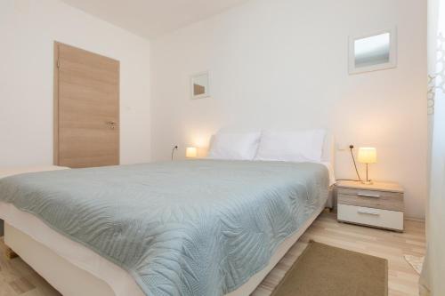 a white bedroom with a large bed and a wooden floor at Apartmani Xenia & Desiderio in Buzet