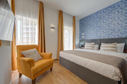 ein Schlafzimmer mit einem großen Bett und einem Stuhl in der Unterkunft Marina Suites & apartments - Self catering - by Tritoni hotels in Gżira