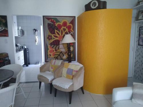 a living room with a chair and a yellow wall at Refúgio Esmeralda in Guarajuba