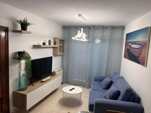 ein Wohnzimmer mit einem blauen Sofa und einem Fernseher in der Unterkunft Ático en Boiro La Niña, a 50m. Playa Jardín. in Boiro