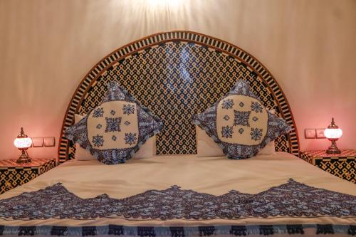 a bed with two pillows on it with two lamps at Riad Fez Mahal in Fès
