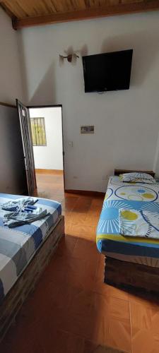 a bedroom with two beds and a flat screen tv at HOTEL CASA COLONIAL in San Antonio del Táchira