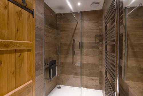a shower with wooden walls and a glass door at Keiras Cottage in Ambleside